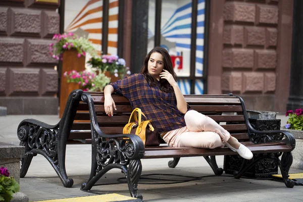Jovem mulher urbana senta-se em um banco — Fotografia de Stock