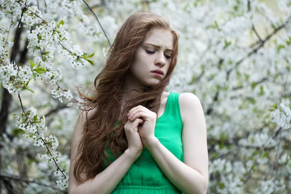 美しい少女は、花の咲く木春 gard の近くに立っています。 — ストック写真