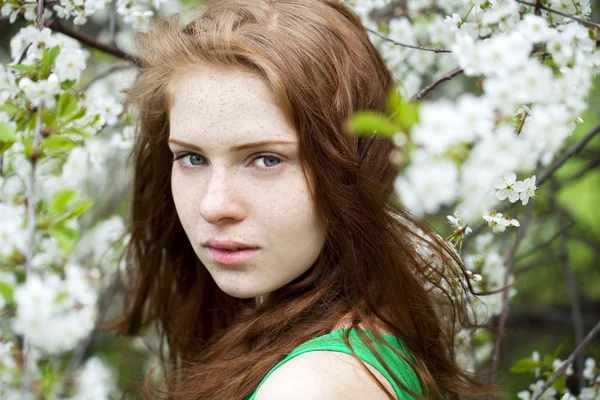 Beautiful young girl standing near blooming trees in spring gard — Stock Photo, Image