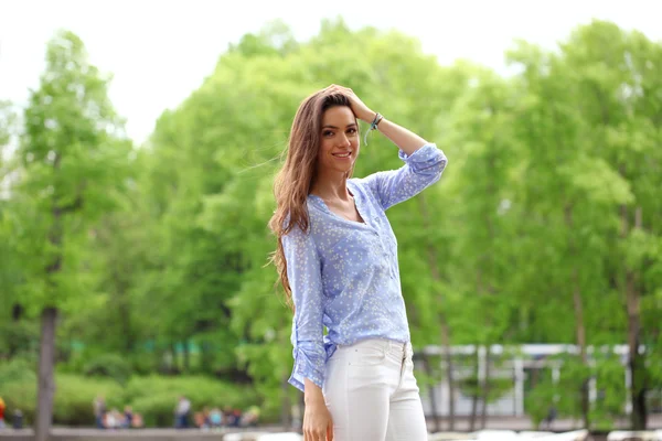 Felice giovane donna in pantaloni bianchi e camicia blu — Foto Stock