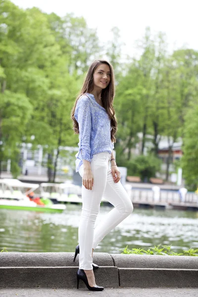 Full längd porträtt av en vacker kvinna i vita byxor och blu — Stockfoto