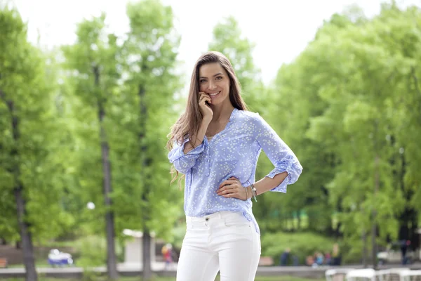 Ευτυχής νεαρή γυναίκα με λευκό παντελόνι και μπλε πουκάμισο — Φωτογραφία Αρχείου