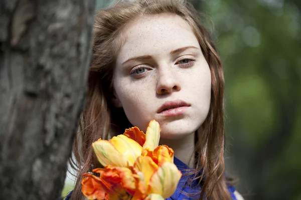 Chica joven en un vestido azul relajante en el parque de primavera — Foto de Stock