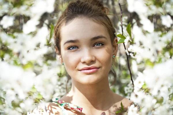 Hermosa chica de pie cerca de árboles en flor en el jardín de primavera —  Fotos de Stock