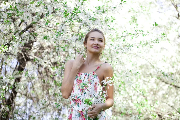Menina bonita de pé perto de árvores florescendo em sarda de primavera — Fotografia de Stock