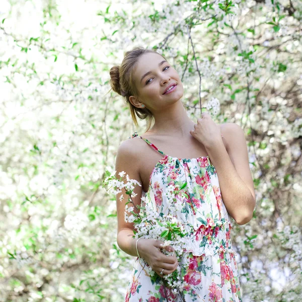 Mooi meisje permanent in de buurt van bloeiende bomen in voorjaar gard — Stockfoto