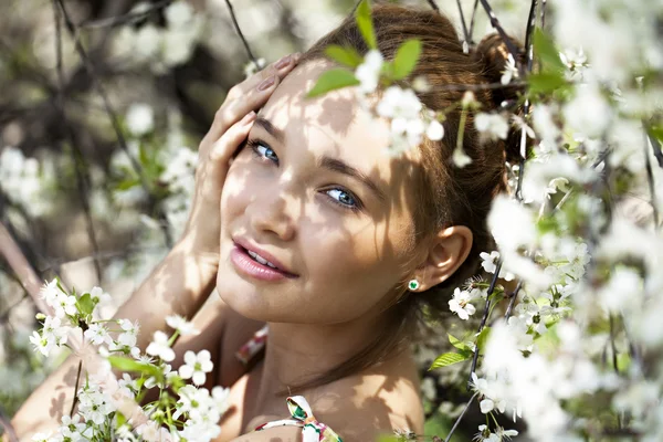 Vacker flicka står nära blommande träd i vårträdgård — Stockfoto