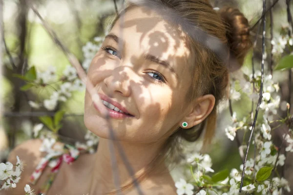 Vacker ung flicka står nära blommande träd i våren gard — Stockfoto