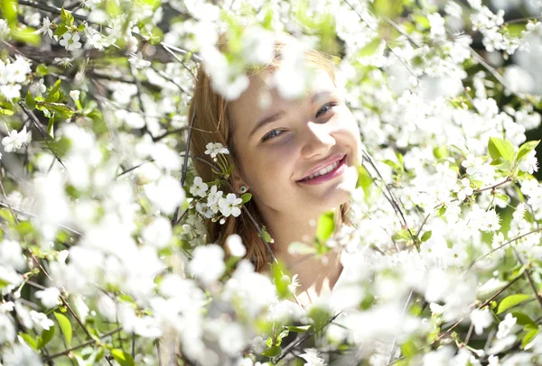 Vacker flicka står nära blommande träd i vårträdgård — Stockfoto