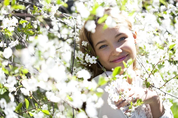 Krásná mladá dívka stojící poblíž kvetoucích stromů na jaře gard — Stock fotografie