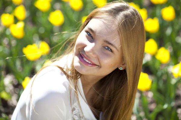 Hermosa joven en el fondo de los tulipanes — Foto de Stock