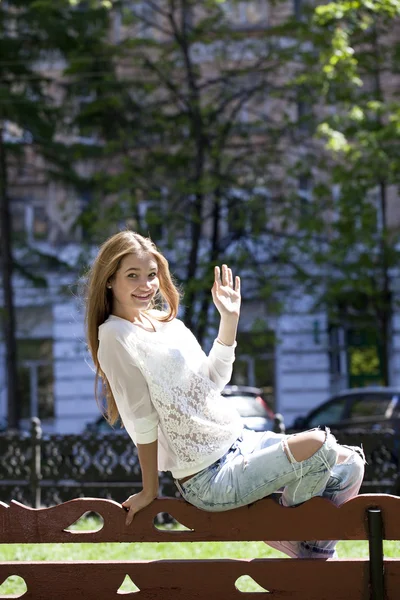 Blondin sitter på en bänk i en sommar park — Stockfoto