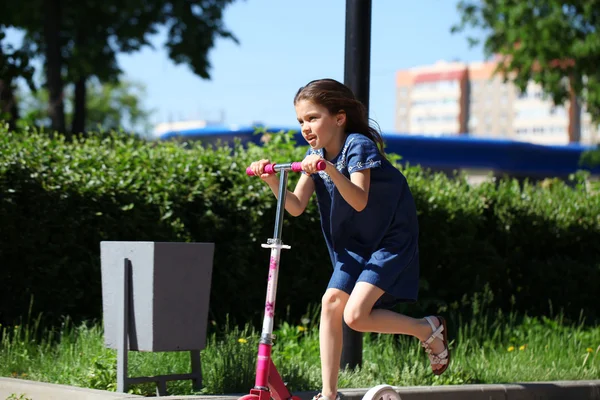 Ragazza felice cavalcando uno scooter in un parco — Foto Stock