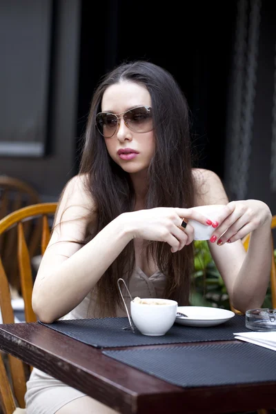 Jovem mulher sentada no café com uma xícara de chá — Fotografia de Stock