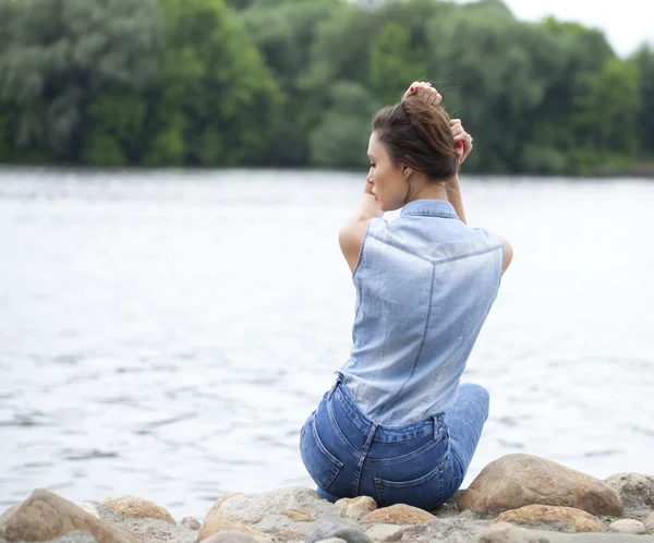 Kayalar üzerine oturan üzgün kadın — Stok fotoğraf