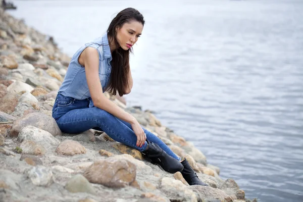 Triest vrouw zitten op de rotsen — Stockfoto