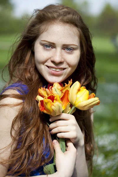 Chica joven en un vestido azul relajante en el parque de primavera — Foto de Stock