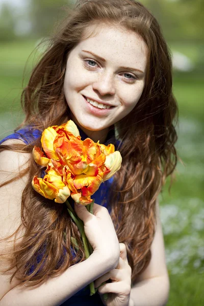 Chica joven en un vestido azul relajante en el parque de primavera — Foto de Stock