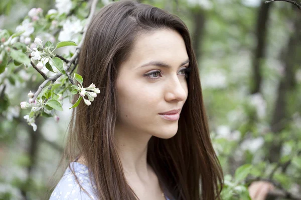 Vacker kvinna som står nära blommande träd i vårträdgård — Stockfoto