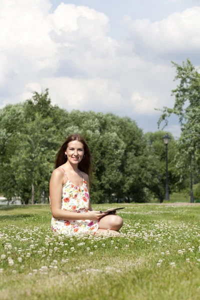 Portrait of young woman sitting on a green lawn — Stock Photo, Image