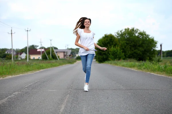 Giovane donna che corre lungo una strada di campagna — Foto Stock