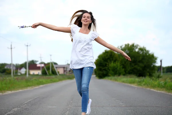 Mladá žena pobíhající po venkovské silnici — Stock fotografie