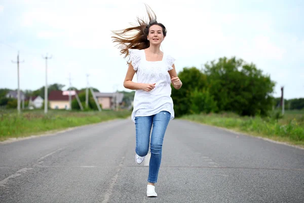 沿着一条乡间小路奔跑的年轻女子 — 图库照片