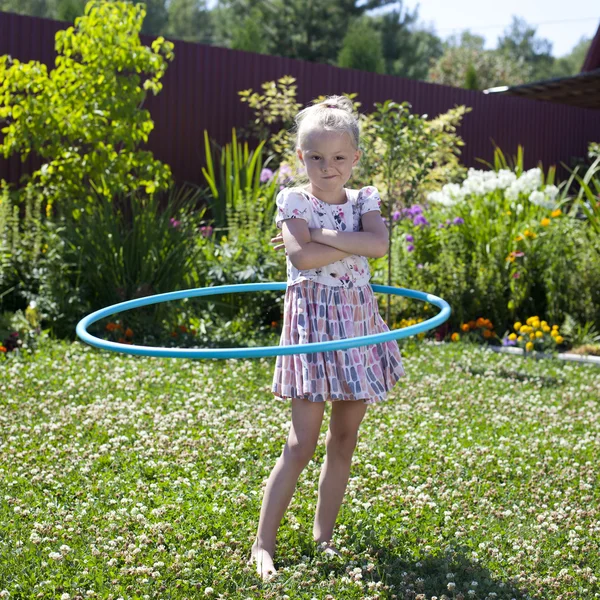 Malá dívka si hraje s hula hoop v její zahradě — Stock fotografie