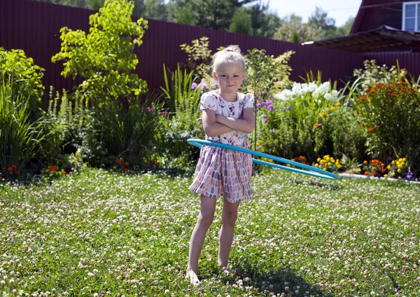 Little girl playing with hula hoop in her garden — Stock Photo, Image