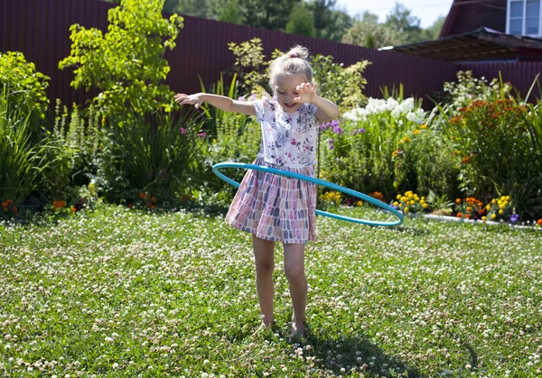 Malá dívka si hraje s hula hoop v její zahradě — Stock fotografie