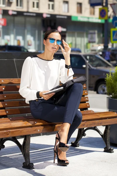 Hermosa mujer de negocios sentada en un banco — Foto de Stock