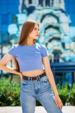 Açık havada, yaz sokağında, kot pantolonlu güzel sarışın bir kızın portresi.