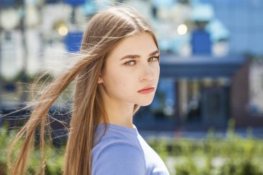 Bir yaz parkının arka planında genç bir kızın yakın plan portresi