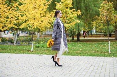 Gri paltolu güzel esmer bir kızın vücut portresi. 