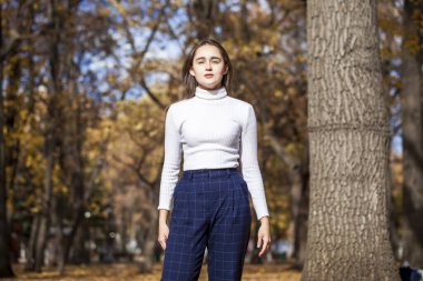 Güz parkında genç ve güzel bir esmer kadının portresi.