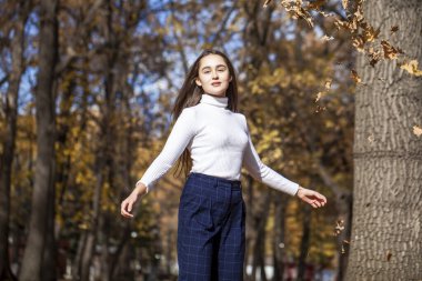 Güz parkında genç ve güzel bir esmer kadının portresi.