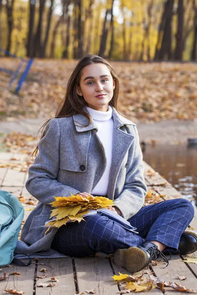 Bir Sonbahar Parkında Ders Kitabıyla Oturan Güzel Bir Kız Öğrenci — Stok fotoğraf