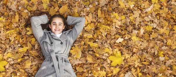 Genç Güzel Bir Kadının Sonbahar Yapraklarında Yatan Portresi — Stok fotoğraf