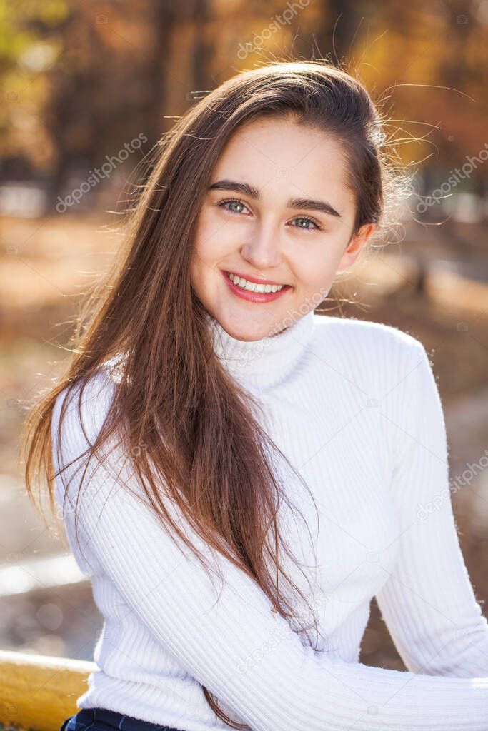 Close up portrait of young brunette girl posing in autumn park