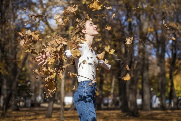 若いです女の子でAウールセーターと黒ジーンズポーズで秋の公園 — ストック写真