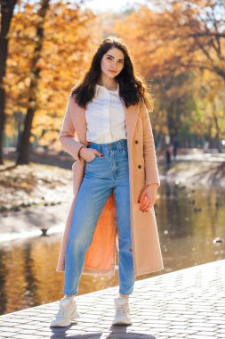 Bir sonbahar parkının arka planında poz veren güzel bir kızın tam boy portresi.