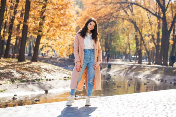 秋の公園を背景にポーズをとる少女の全長の肖像画 — ストック写真