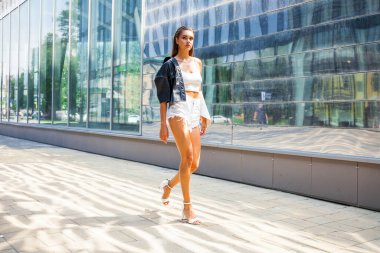 Yaz caddesinde yürüyen güzel esmer bir kızın vücut portresi.