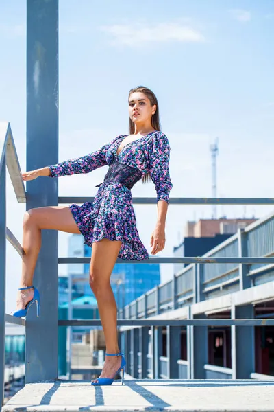 Arka planda mavi bir gökyüzünde poz veren güzel esmer bir kadının bütün vücut portresi.