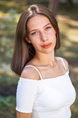 Yüzünde çiller olan güzel kahverengi saçlı bir kızın portresi.