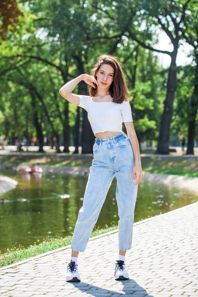 全长的肖像画 穿着蓝色牛仔裤的年轻漂亮的姑娘在夏日的公园里摆姿势 — 图库照片