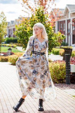 Güz sokağında poz veren sarışın genç kadının tam boy portresi.