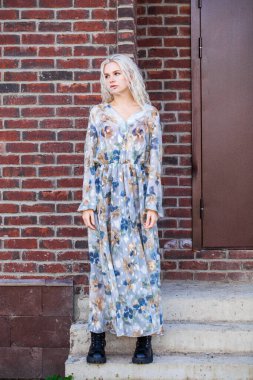 Güz sokağında poz veren sarışın genç kadının tam boy portresi.