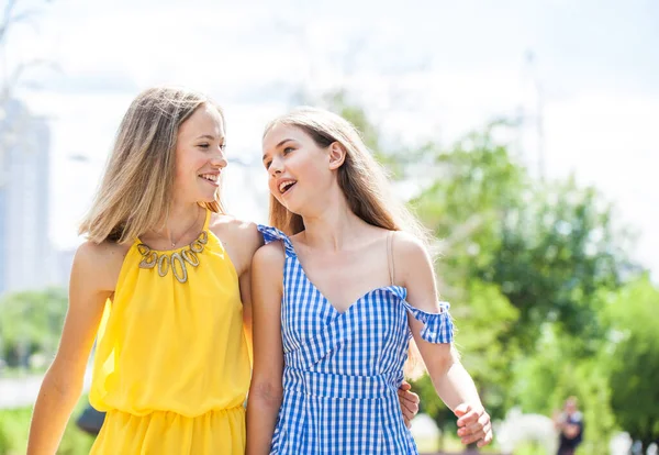 两个穿着夏装的快乐的女朋友在阳光明媚的大街上散步 — 图库照片