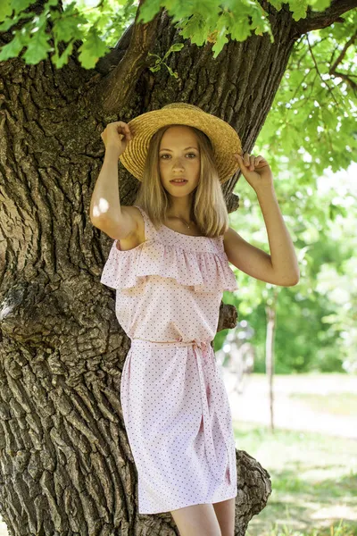 一个穿着夏装的年轻漂亮姑娘在橡木树荫下摆姿势的画像 — 图库照片